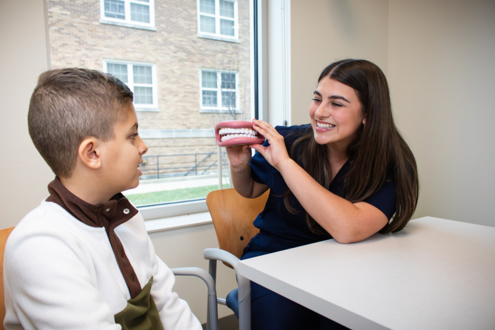 An SLP using a model of a mouth to show a patient how to pronounce certain sounds