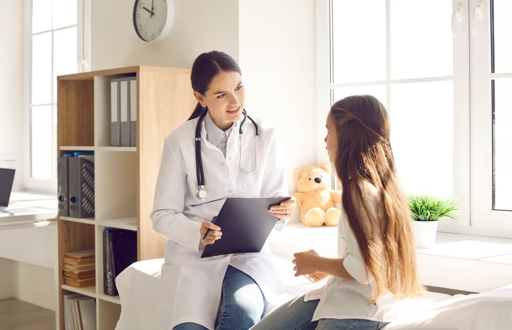 A nurse practitioner talking to their young patient