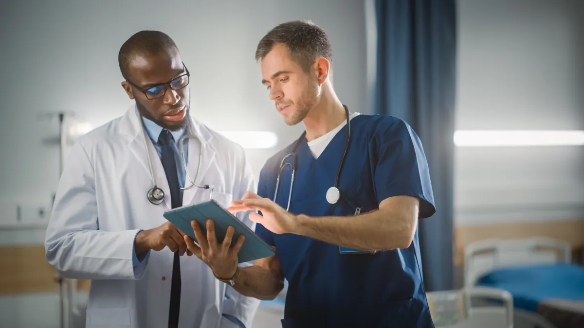 male nurse speaking with male doctor over clipboard notes