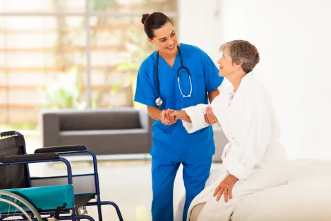Nurse in a white coat helping an older adult patient.